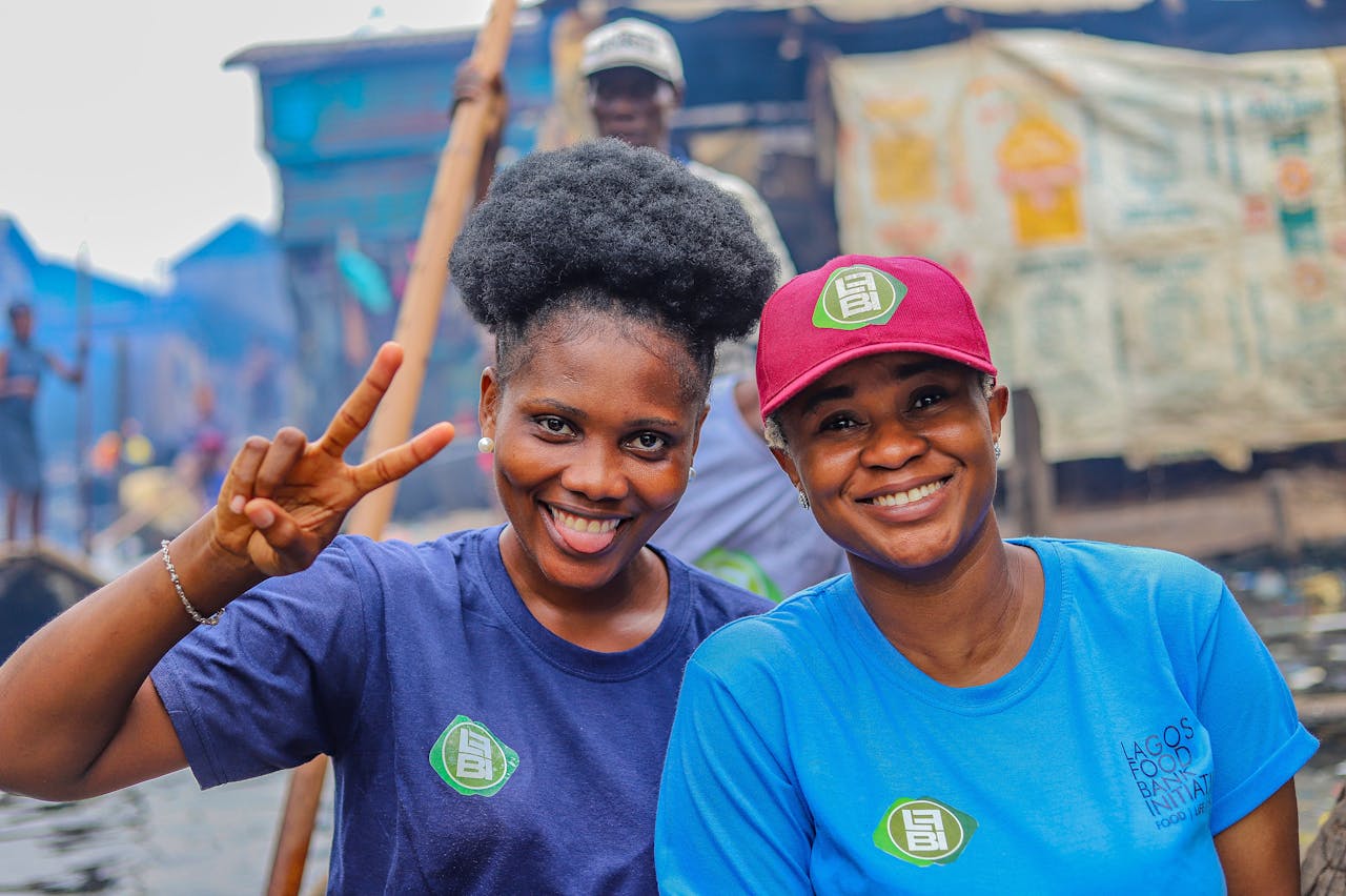 Two women volunteering in Lagos, Nigeria, happily posing with peace signs in a community setting.
